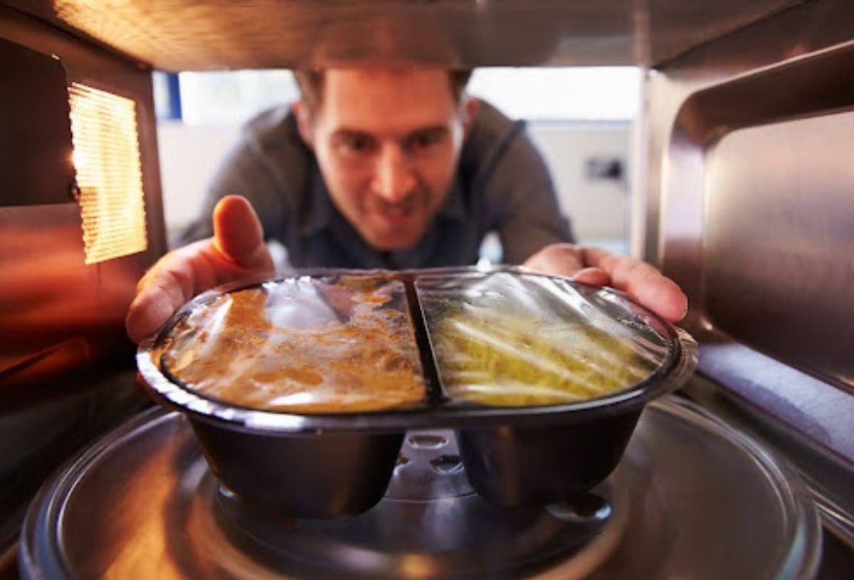 a man put food into a microwave oven